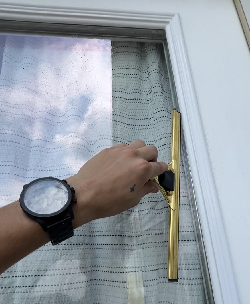 Squeegee gliding across a soapy residential window